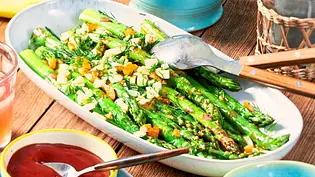 Gegrillter grüner Spargel auf einer ovalen Platte mit angelegtem Servierbesteck - Foto: LECKER @ Bauer Media Group Gegrillter grüner Spargel auf einer ovalen Platte mit angelegtem Servierbesteck - Foto: LECKER @ Bauer Media Group