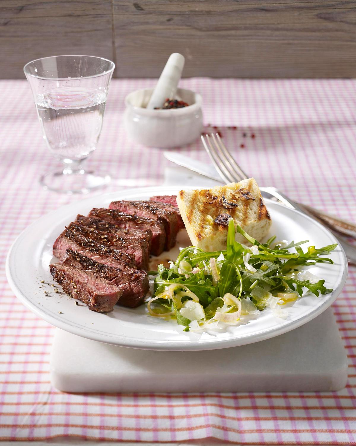 Gegrilltes Rumpsteak auf Rucola-Salat mit feinen Parmesanspänen und Knoblauch-Baguette Rezept