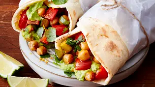 Zwei nebeneinander liegende Wraps in etwas Brotpapier gewickelt und gefülllt mit Kichererbsen, Gemüse und Guacamole. - Foto: LECKER @ Bauer Media Group Zwei nebeneinander liegende Wraps in etwas Brotpapier gewickelt und gefülllt mit Kichererbsen, Gemüse und Guacamole. - Foto: LECKER @ Bauer Media Group