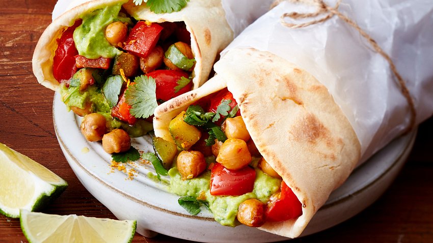 Zwei nebeneinander liegende Wraps in etwas Brotpapier gewickelt und gefülllt mit Kichererbsen, Gemüse und Guacamole. - Foto: House of Food / Bauer Food Experts KG