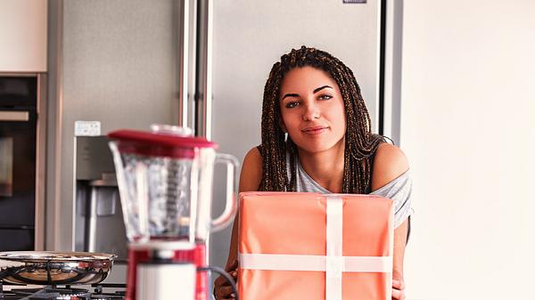 Studentin mit Geschenk in ihrer Küche - Foto: LECKER.de/iStock (Giulio Fornasar)