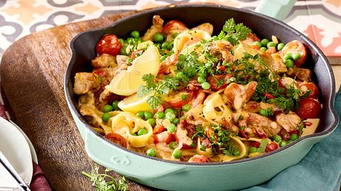 In einer PFanne ist Geschnetzeltes mit Erbsen, Zitronenscheiben, Tomaten und Kräutern appetitlich angerichtet - Foto: House of Food / Bauer Food Experts KG