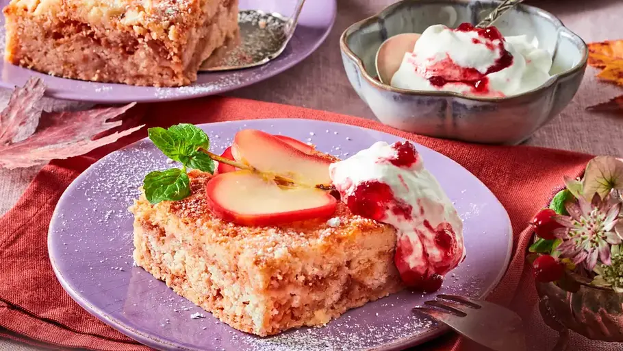 Das Tüpfelchen auf dem i ist ein Klecks Preiselbeersahne Apfelkuchen im Viereck mit Apfeldeko und Sahne