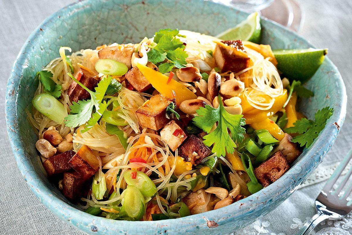 Frischer Glasnudelsalat mit Mango, Tofu, Frühlingszwiebeln, Koriander und Limette in einer türkisen Schale angerichtet.