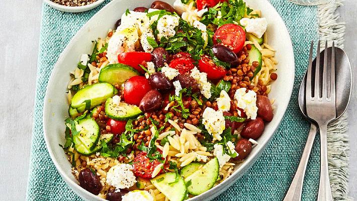Griechischer Nudelsalat mit Kirschtomaten, Gurke, Oliven und Linsen in einer weißen ovalen Aufflaufform - Foto: House of Food / Bauer Food Experts KG
