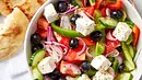 Eine Schüssel Griechischer Salat mit Gurke, Tomaten, schwarzen Oliven, Feta und Paprika steht auf einem Tisch neben Fladenbrot - Foto: LECKER @ Bauer Media Group Eine Schüssel Griechischer Salat mit Gurke, Tomaten, schwarzen Oliven, Feta und Paprika steht auf einem Tisch neben Fladenbrot - Foto: LECKER @ Bauer Media Group