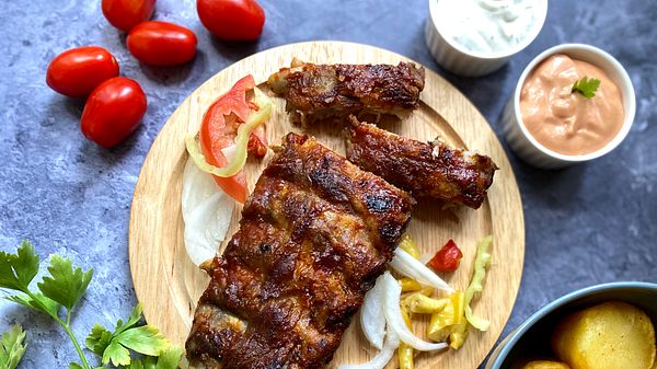 Gegrillte Spare Ribs mit Beilagen auf einem Holzbrett - Foto: iStock/Julia Nagy