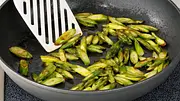 Goldbraun gebratene grüne Spargelstücke werden in einer Pfanne angebraten - Foto: LECKER @ Bauer Media Group