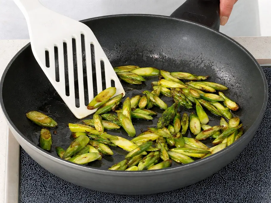 Grünen Spargel braten Goldbraun gebratene grüne Spargelstücke werden in einer Pfanne angebraten