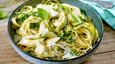 Spaghetti mit Zucchinistreifen, heller Sauce, Käsehobeln und Basilikum liegen in einer Schale auf einem Holztisch. - Foto: LECKER @ Bauer Media Group Spaghetti mit Zucchinistreifen, heller Sauce, Käsehobeln und Basilikum liegen in einer Schale auf einem Holztisch. - Foto: LECKER @ Bauer Media Group