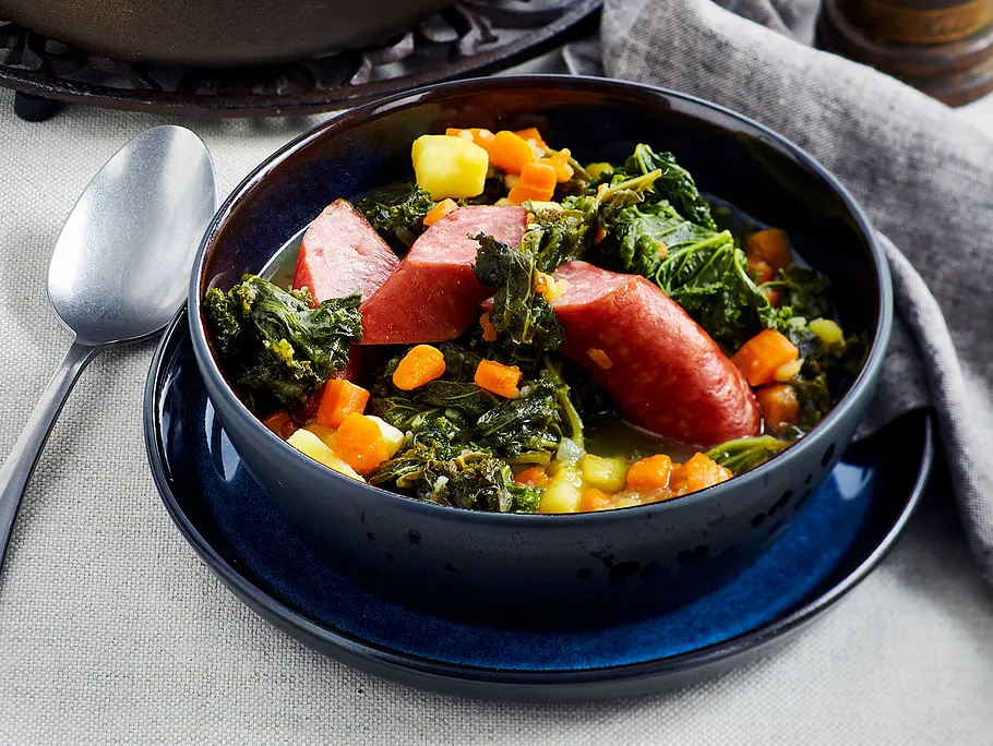 Grünkohleintopf mit Kartoffeln Rezept Grünkohleintopf mit Kartoffeln, Möhren und Mettenden in einem tiefen blauen Teller serviert. Rezept