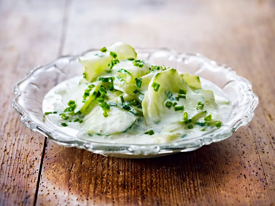 Gurkensalat mit Sahne Rezept Gurkensalat mit cremigem Sahnedressing, serviert in einer gläsernen Schale und mit frischem Schnittlauch bestreut