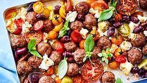Hackbällchen, bunte Kirschtomatenund Oliven mit Feta und Basilikum auf einem großen Backblech.  - Foto: House of Food / Bauer Food Experts KG
