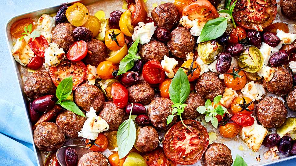 Hackbällchen, bunte Kirschtomatenund Oliven mit Feta und Basilikum auf einem großen Backblech.  - Foto: House of Food / Bauer Food Experts KG