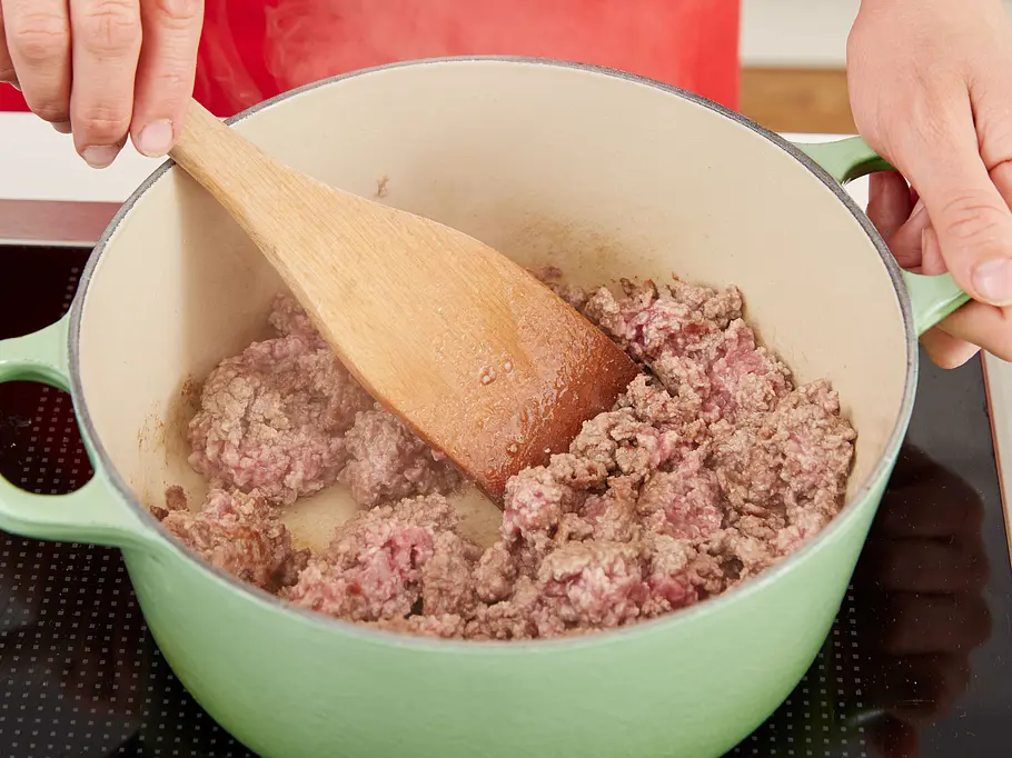 Hackfleisch für Käse-Lauch-Suppe braten Hackfleisch wird in einem grünen Topf krümelig angebraten
