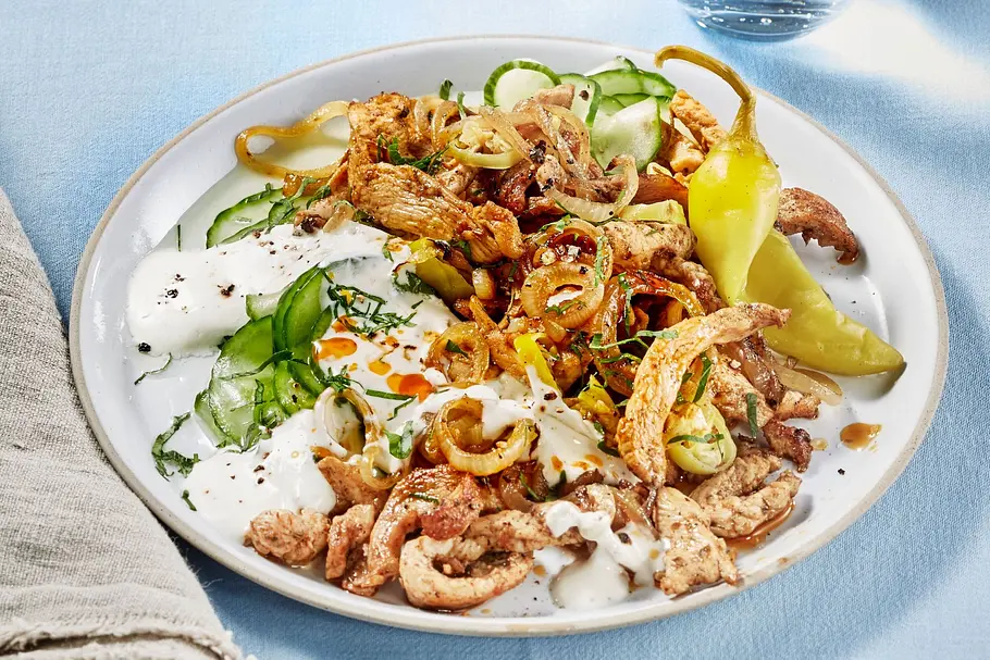 Hähnchen Gyros aus dem Airfryer Hähnchen Gyros aus dem Airfryer mit einem Joghurt-Gurken-Dip und einer Peperoni auf einem cremefarbenen Teller.