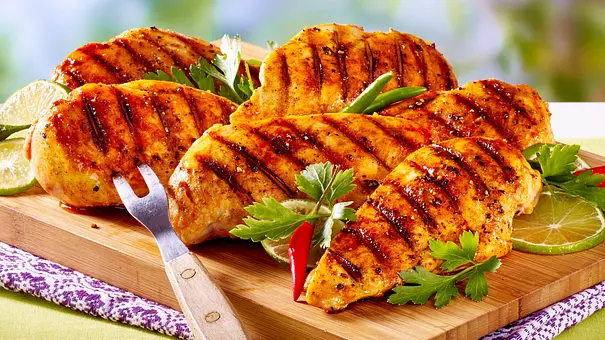 Mehrere gegrillte Hähnchenbrüstchen mit deutlichen Grillstreifen liegen auf einem Holzbrett. - Foto: LECKER @ Bauer Media Group