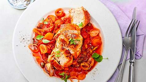 Hähnchen in Paprika-Tomaten-Sugo auf einem weißen Teller serviert.  - Foto: House of Food / Food Experts KG
