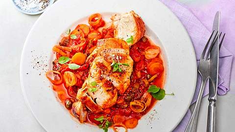 Hähnchen in Paprika-Tomaten-Sugo auf einem weißen Teller serviert.  - Foto: House of Food / Food Experts KG