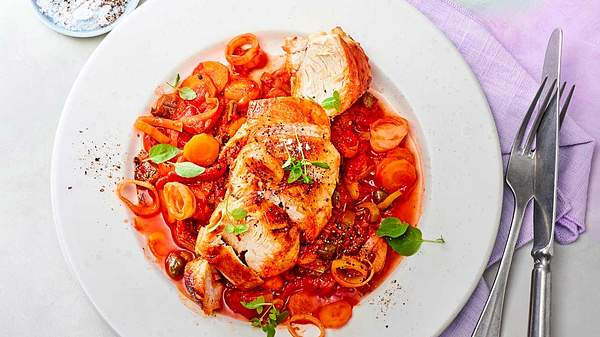 Hähnchen in Paprika-Tomaten-Sugo auf einem weißen Teller serviert.  - Foto: House of Food / Food Experts KG