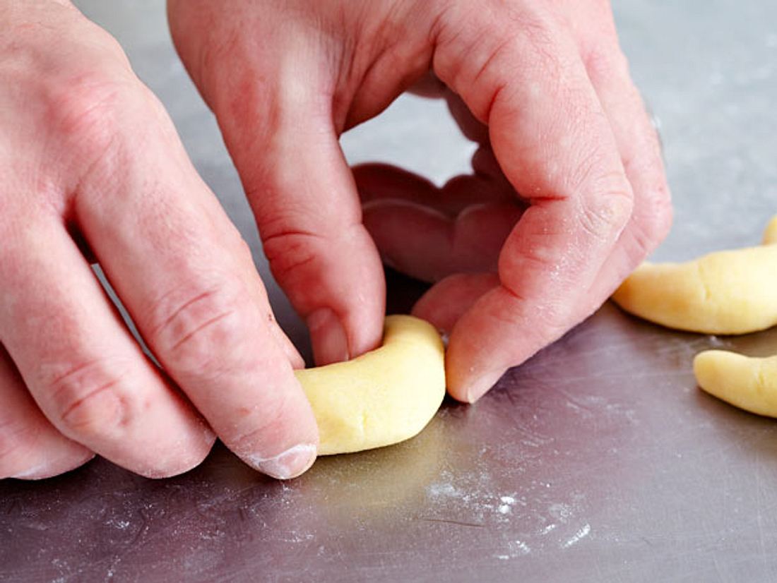 Vanillekipferl-Teig mit den Händen zu Halbmonden formen