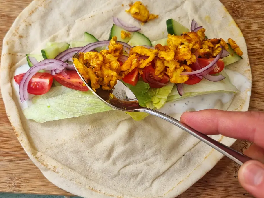 Halloumi-Shawarma füllen Die Halloumi-Füllung wird aufs Fladenbrot gegeben.