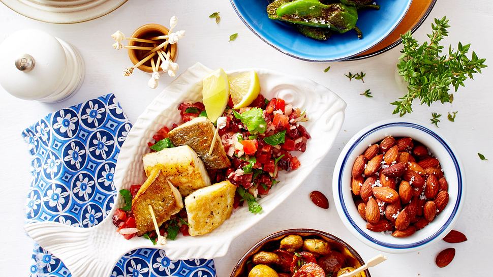 Teller gefüllt mit Doradenfiets auuf einem Sommersalat aus Tomate und Zwiebeln, erziert mit Petersilie und beiliegenden Zitronenscheiben. - Foto: House of Food / Bauer Food Experts KG
