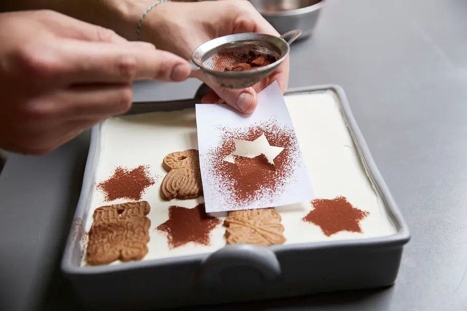 Mit einer Stern-Schablone das Tiramisu mit Kakao bestäuben.
