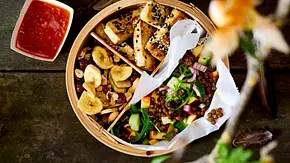 Knusprig gebratener Tofu in Sesamkruste, serviert in einer runden Bambusschale mit frischer Linsen-Gemüse-Mischung und einer süßscharfen Dip-Sauce in einer kleinen weißen Schale. - Foto: LECKER @ Bauer Media Group Knusprig gebratener Tofu in Sesamkruste, serviert in einer runden Bambusschale mit frischer Linsen-Gemüse-Mischung und einer süßscharfen Dip-Sauce in einer kleinen weißen Schale. - Foto: LECKER @ Bauer Media Group