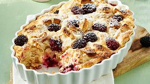Süßer Quarkauflauf mit Brombeeren und Puderzucker in einer weißen Auflaufform. - Foto: LECKER @ Bauer Media Group