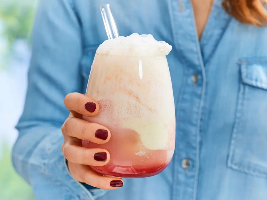 Erdbeer Float mit schaumiger Krone und einer Kugel Zitronensorbet in einem runden Glas, mit Strohhalm serviert.
