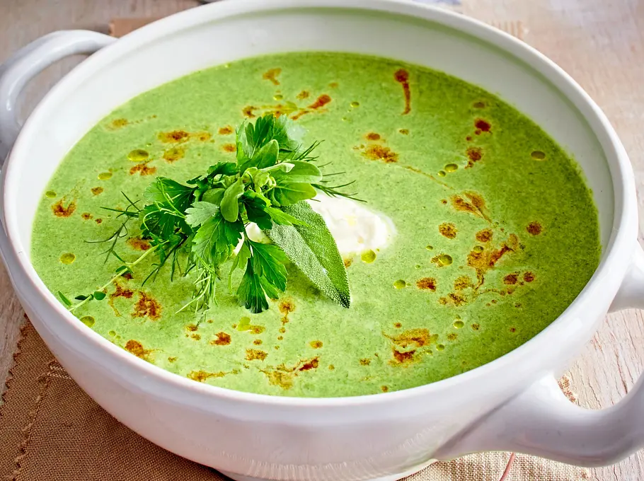 Schüssel gefüllt mit einer grünen Spinat Kartoffel Suppe mit ein paar Ölspritzern oben drauf und Kräutern
