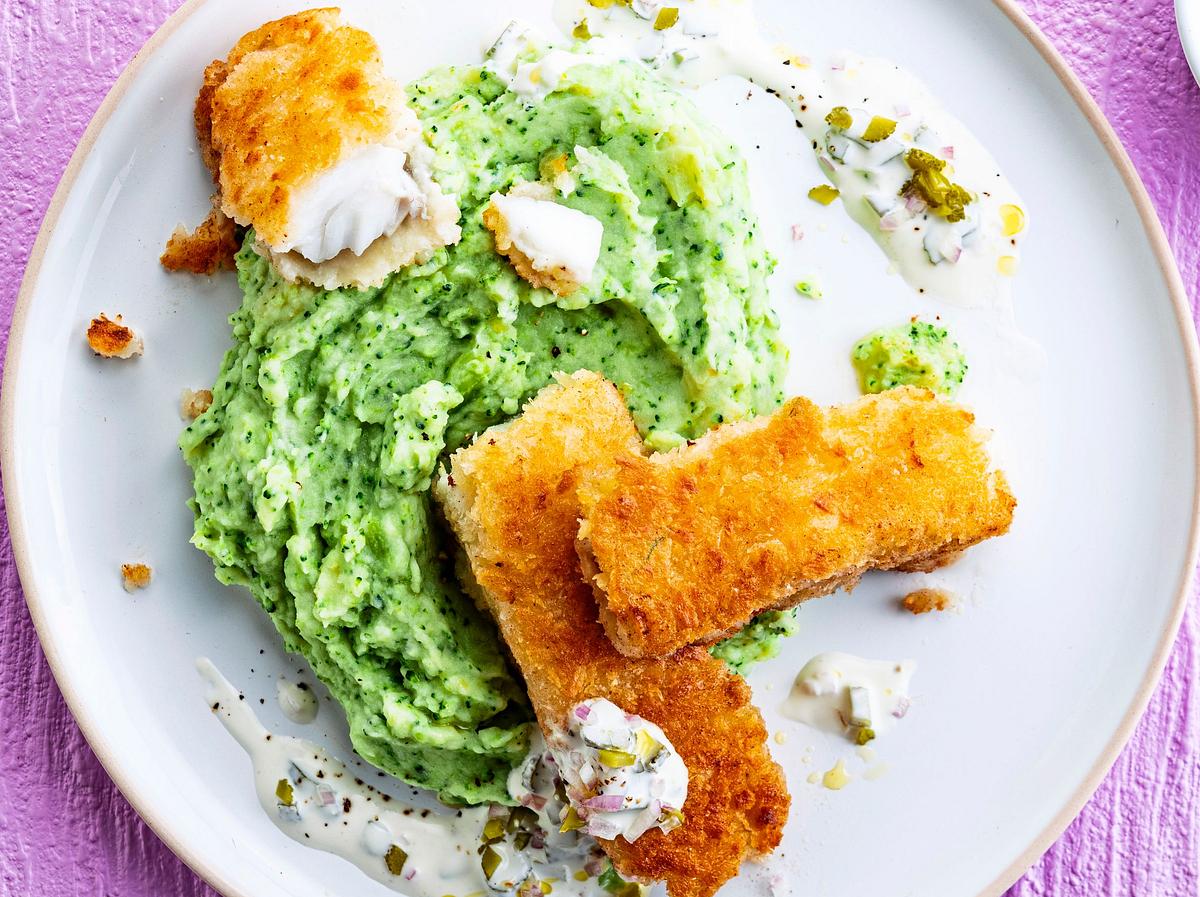 Auf einem Teller liegen Fischstäbchen auf einem Haufen as Brokkoli-Püree, getopped mit etwa Remulade