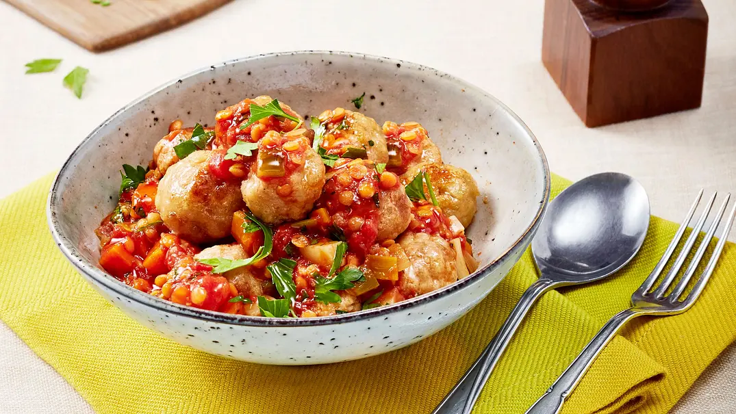In einer weißen Keramikschale sind Knödel in einer roten Soße mit Linsen und grüner Petersilie angerichtet - Foto: LECKER @ Bauer Media Group In einer weißen Keramikschale sind Knödel in einer roten Soße mit Linsen und grüner Petersilie angerichtet - Foto: LECKER @ Bauer Media Group