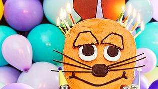 Ein Schokokuchen in der Form der berühmten Maus. Er ist verziert mit Geburtstagskerzen - Foto: LECKER @ Bauer Media Group