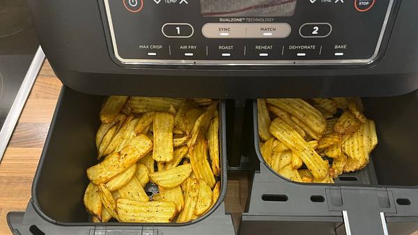 Ein Airfryer mit frischen Pommes und Küchenutensilien auf einer Küchenzeile - Foto: LECKER.de/ Franziska Hoppe