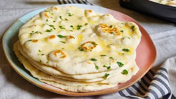 Pfannenbrot gestapelt auf einem Teller und mit Kräuterbutter bestrichen. - Foto: LECKER @ Bauer Media Group / Max Bergmann