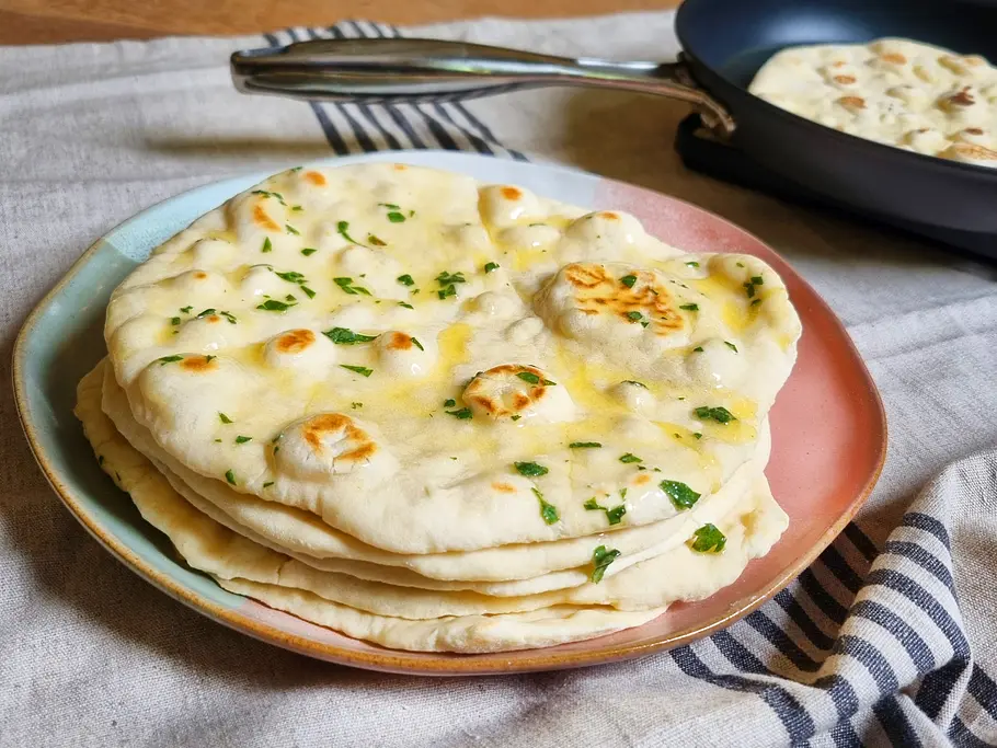 High-Protein Pfannenbrot Rezept Pfannenbrot gestapelt auf einem Teller und mit Kräuterbutter bestrichen.