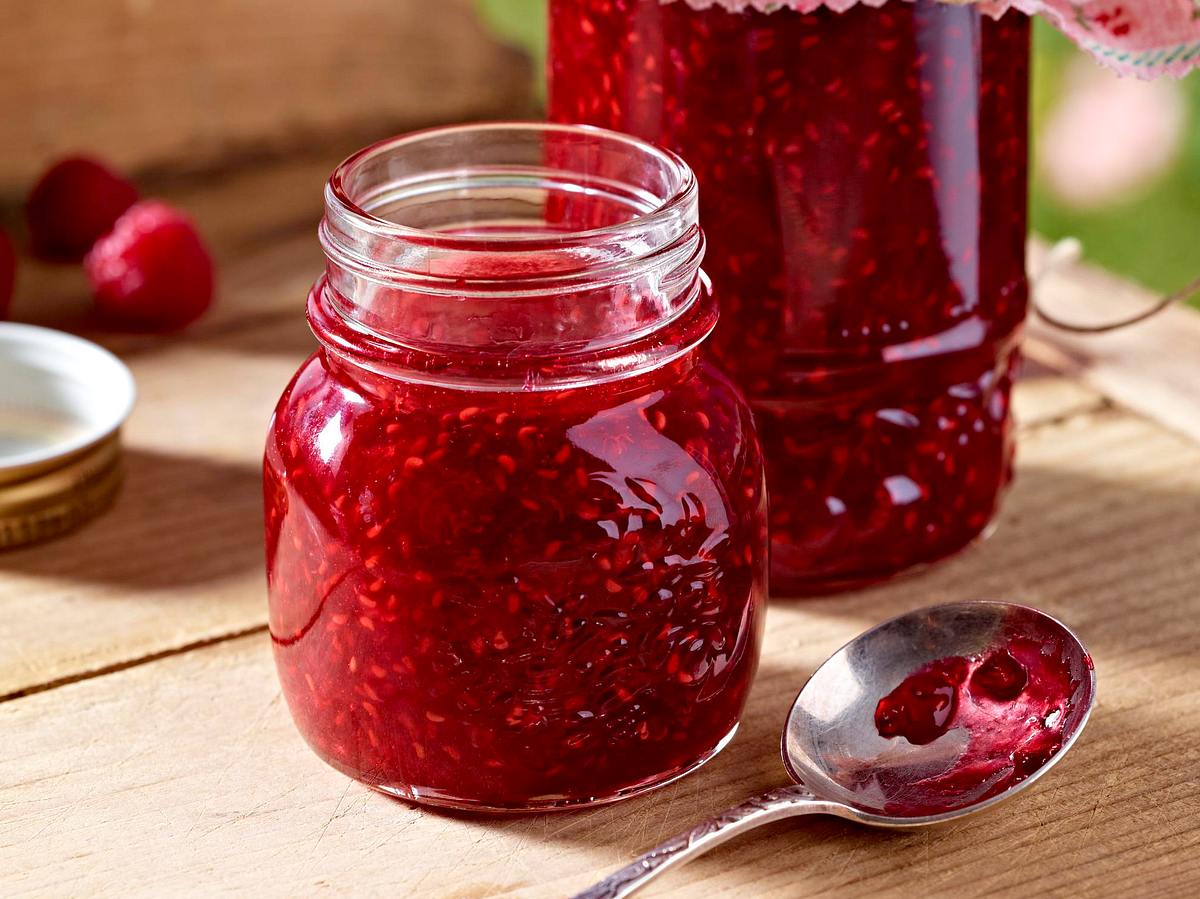 Himbeermarmelade in einem Glas gefüllt mit Teelöffel seitlich