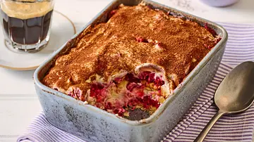 Tiramisu mit einer Schicht Kakao, frischen Himbeeren und Butterkeksen in einer rechteckigen Auflaufform auf einem gestreiften Tuch. - Foto: StockFood Studios / Meike Bergmann