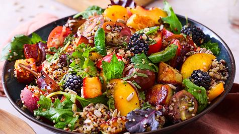 In einer Schüssel angerichteter Salat, mit Halloumi-Pfirsich mit Quinoa. Das ganze ist mit einem Dressing durchzogen mit Körner, Salat und Brombeeren drauf. - Foto: House of Food / Bauer Food Experts KG