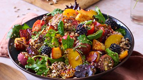 In einer Schüssel angerichteter Salat, mit Halloumi-Pfirsich mit Quinoa. Das ganze ist mit einem Dressing durchzogen mit Körner, Salat und Brombeeren drauf. - Foto: Image Professionals