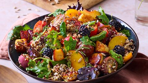 In einer Schüssel angerichteter Salat, mit Halloumi-Pfirsich mit Quinoa. Das ganze ist mit einem Dressing durchzogen mit Körner, Salat und Brombeeren drauf. - Foto: Image Professionals