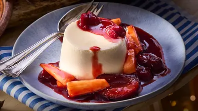 Chai-Parfait als cremiges Dessert, serviert mit aromatischen Rumfrüchten wie Kirschen und Orangen in fruchtiger Sauce auf einem Teller. - Foto: LECKER @ Bauer Media Group