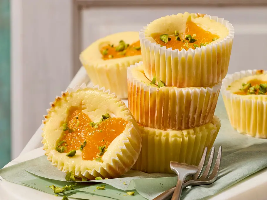 Käsekuchen-Muffins, dekoriert mit zu Schmetterlingen gelegten Mandarinenscheiben.
