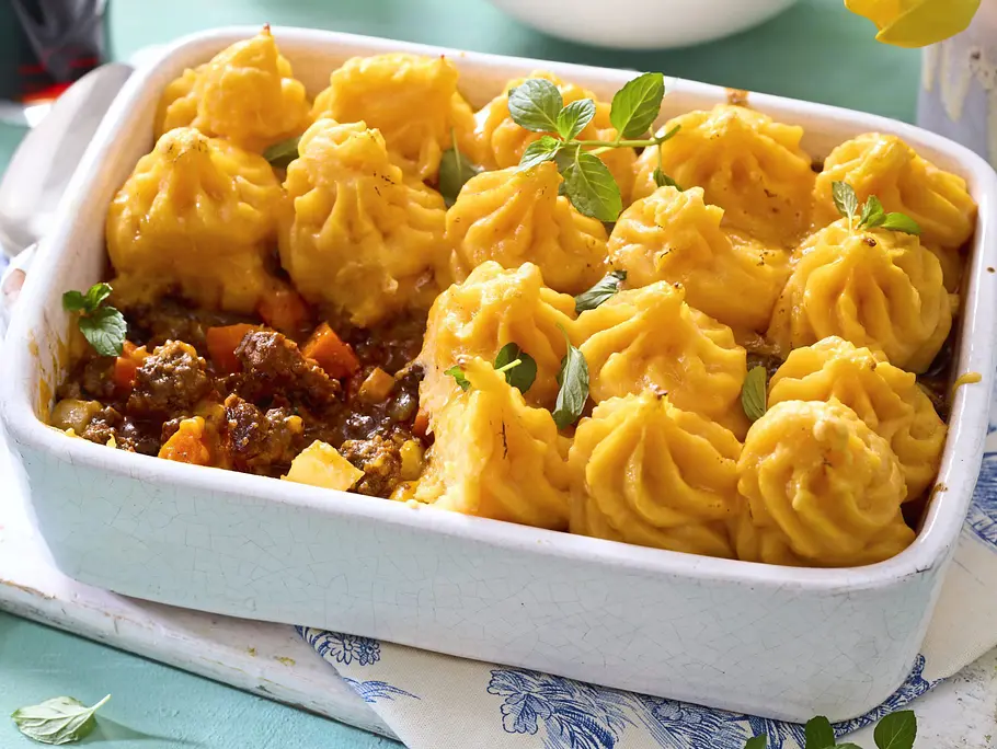 Shepherd's Pie Rezept Shepherd’s Pie mit goldbraun gratiniertem Kartoffelpüree-Topping in einer weißen, rechteckigen Auflaufform, darunter eine würzige Hackfleisch-Gemüse-Schicht.