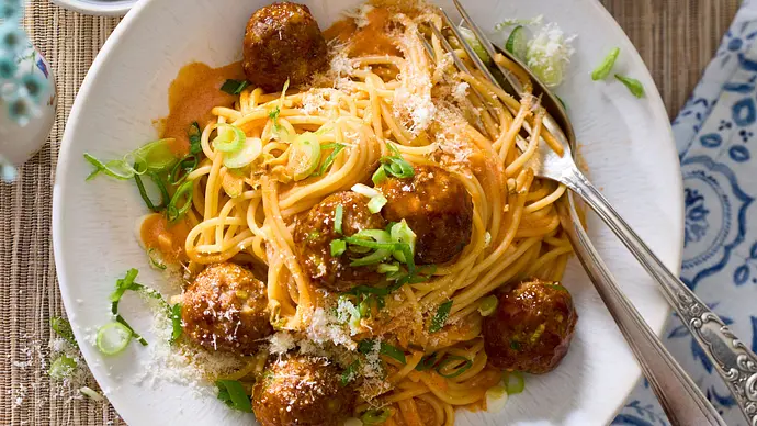 Spaghetti in cremiger Gochujang-Sauce mit würzigen Hackbällchen, garniert mit Frühlingszwiebeln und geriebenem Käse, auf einem weißen Teller serviert. - Foto: LECKER @ Bauer Media Group
