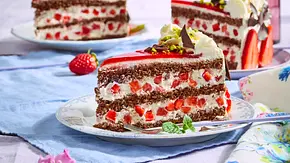 Stück festliche Erdbeertorte mit lockeren Schokobiskuit-Schichten, Sahnecreme und frischen Erdbeerstückchen, garniert mit Schokolade, Pistazien und Sahnetupfen auf einem weißen Teller. - Foto: LECKER @ Bauer Media Group Stück festliche Erdbeertorte mit lockeren Schokobiskuit-Schichten, Sahnecreme und frischen Erdbeerstückchen, garniert mit Schokolade, Pistazien und Sahnetupfen auf einem weißen Teller. - Foto: LECKER @ Bauer Media Group