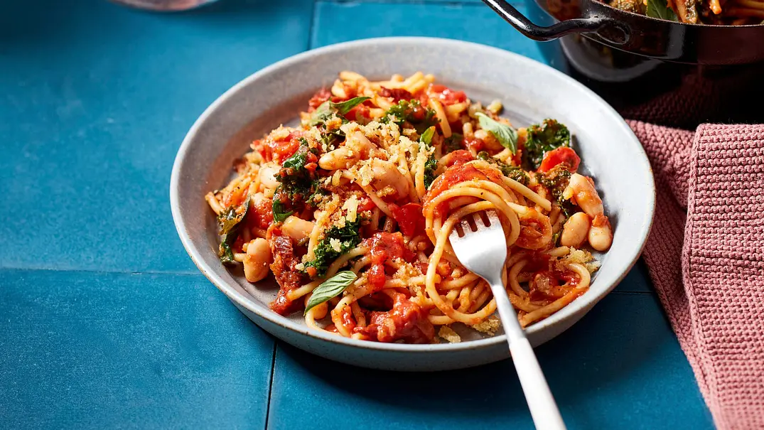 Spaghetti mit Grünkohl und weißen Bohnen in einer kräftigen Tomatensauce, serviert auf einem grauen Teller. - Foto: LECKER @ Bauer Media Group Spaghetti mit Grünkohl und weißen Bohnen in einer kräftigen Tomatensauce, serviert auf einem grauen Teller. - Foto: LECKER @ Bauer Media Group