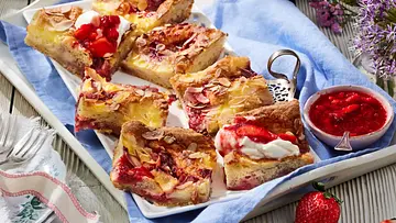 Mehrere Stücke Erdbeer-Butterkuchen mit goldbrauner Kruste, cremiger Puddingfüllung, Erdbeerstückchen und gerösteten Mandelblättchen, angerichtet auf einer rechteckigen weißen Platte mit blauem Tuch. - Foto: LECKER @ Bauer Media Group Mehrere Stücke Erdbeer-Butterkuchen mit goldbrauner Kruste, cremiger Puddingfüllung, Erdbeerstückchen und gerösteten Mandelblättchen, angerichtet auf einer rechteckigen weißen Platte mit blauem Tuch. - Foto: LECKER @ Bauer Media Group